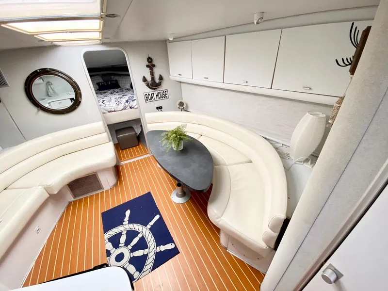 Slide: The Image of 1989 Mainship 39 Mediterranean Express interior with curved seating, nautical decor, and wood flooring. - 10