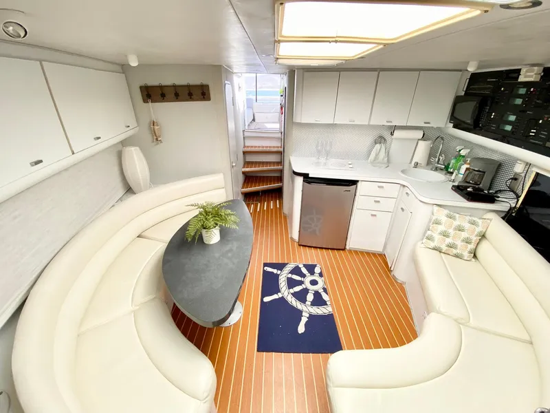 Slide: The Image of 1989 Mainship 39 Mediterranean Express interior with white seating, kitchenette, and nautical decor. - 9