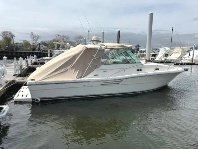 Slide: The Image of 2001 Pursuit 3000 Express boat docked in a marina, covered with a beige canopy. - 0
