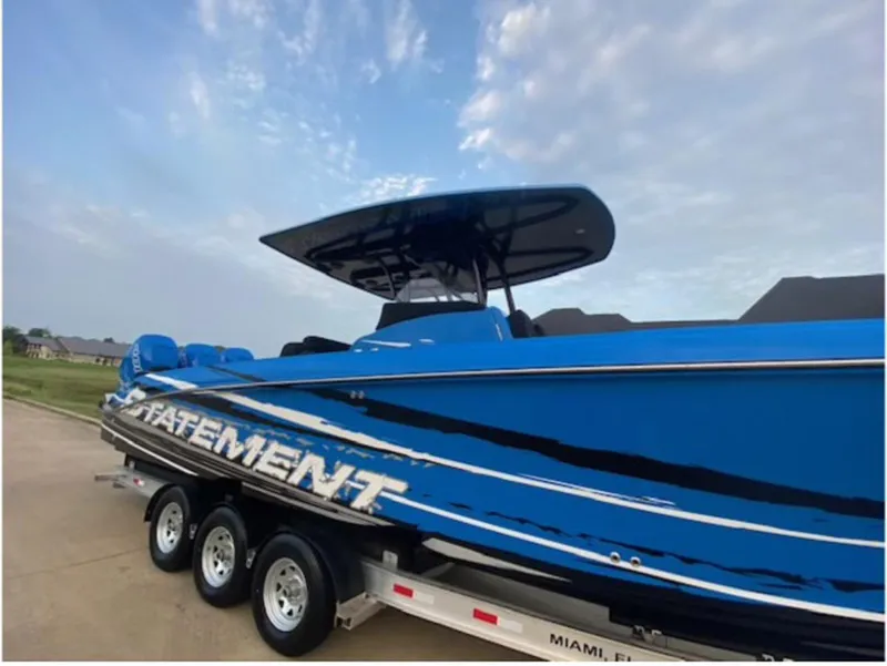 Slide: The Image of 2021 Statement 380 Open boat in blue on a trailer, under a cloudy sky. - 4