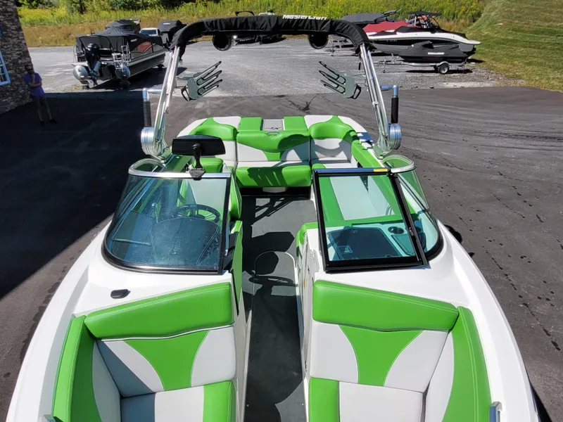 Slide: The Image of 2019 MasterCraft XT23 boat with green and white interior, parked on asphalt. - 11