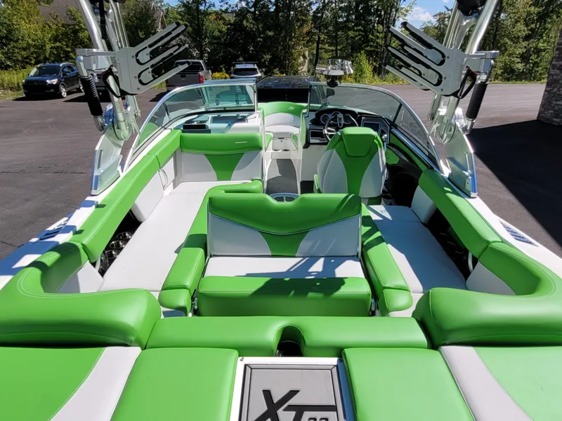 Slide: The Image of 2019 MasterCraft XT23 boat interior with green and white seating, parked outdoors. - 15