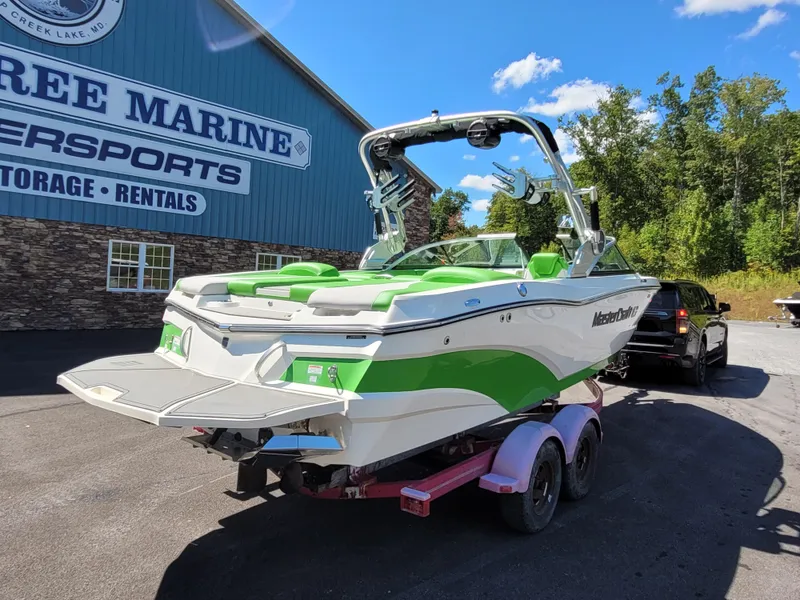 Slide: The Image of 2019 MasterCraft XT23 boat with green accents on a trailer outside a marine shop. - 4