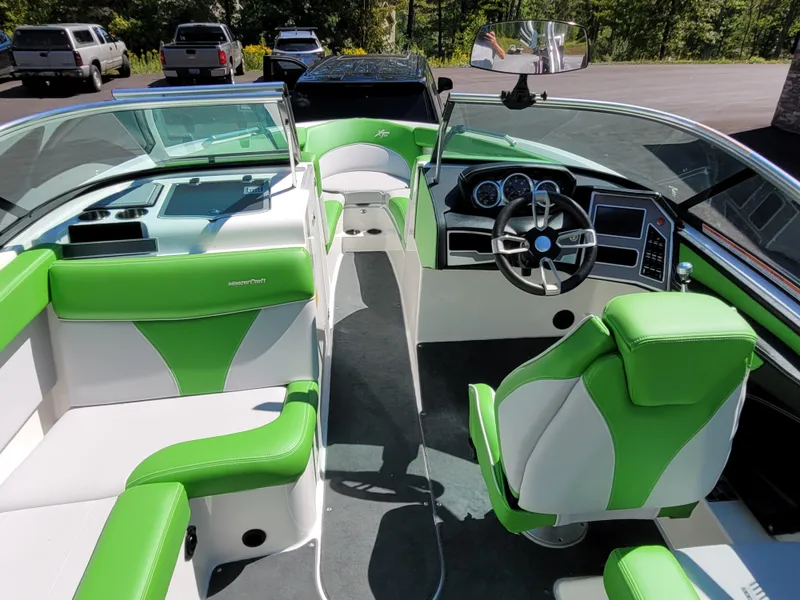 Slide: The Image of 2019 MasterCraft XT23 boat interior with green and white seating, modern dashboard, and steering wheel. - 8