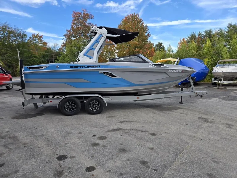 Slide: The Image of 2023 Centurion Ri230 boat on trailer, blue and gray, parked outdoors. - 0