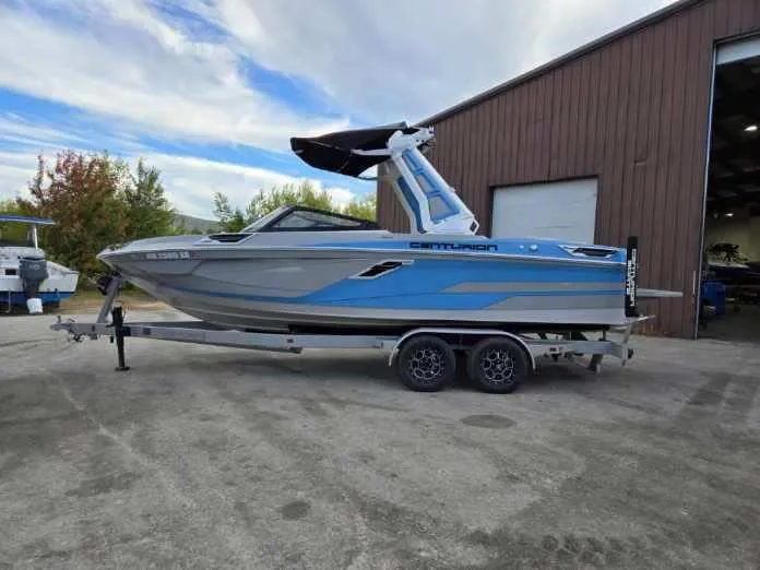 Slide: The Image of 2023 Centurion Ri230 boat on trailer outside warehouse. - 2