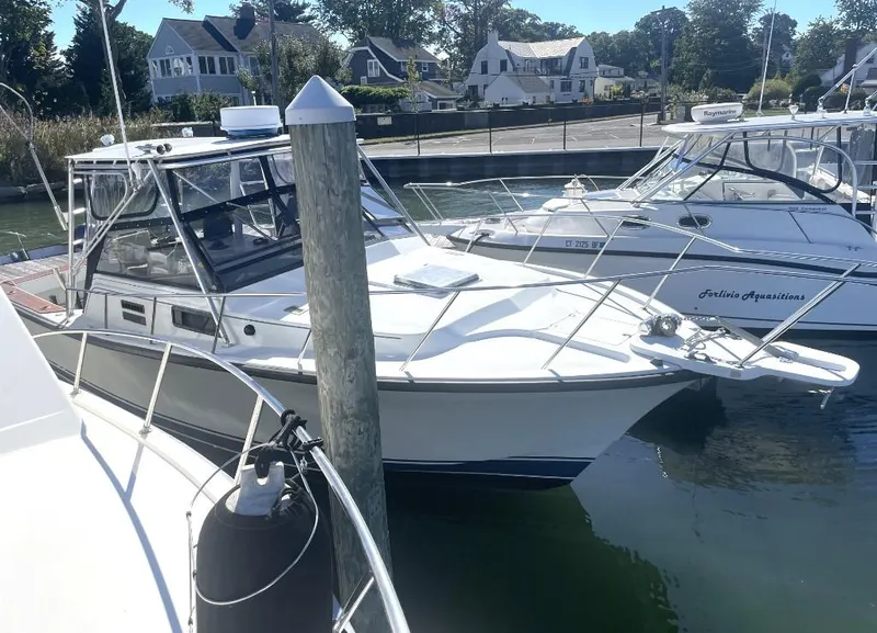 Slide: The Image of 1987 Rampage 31 Express boat docked in a marina, surrounded by other vessels. - 0