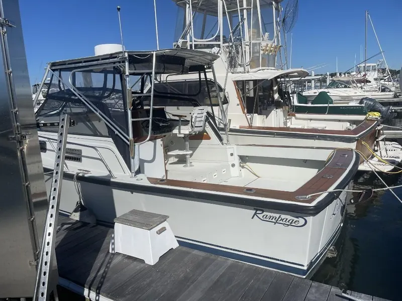Slide: The Image of 1987 Rampage 31 Express boat docked at marina under clear blue sky. - 2