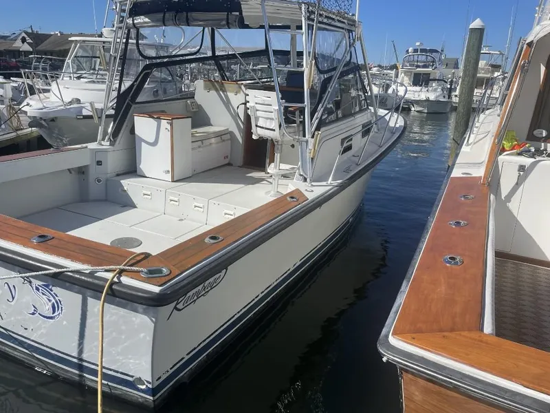 Slide: The Image of 1987 Rampage 31 Express boat docked in marina, featuring spacious deck and seating area. - 4