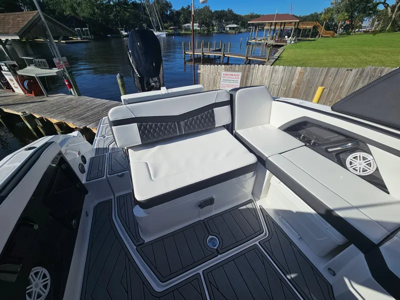 Slide: The Image of 2025 Monterey 255SS boat interior with seating, docked by a scenic waterfront. - 11