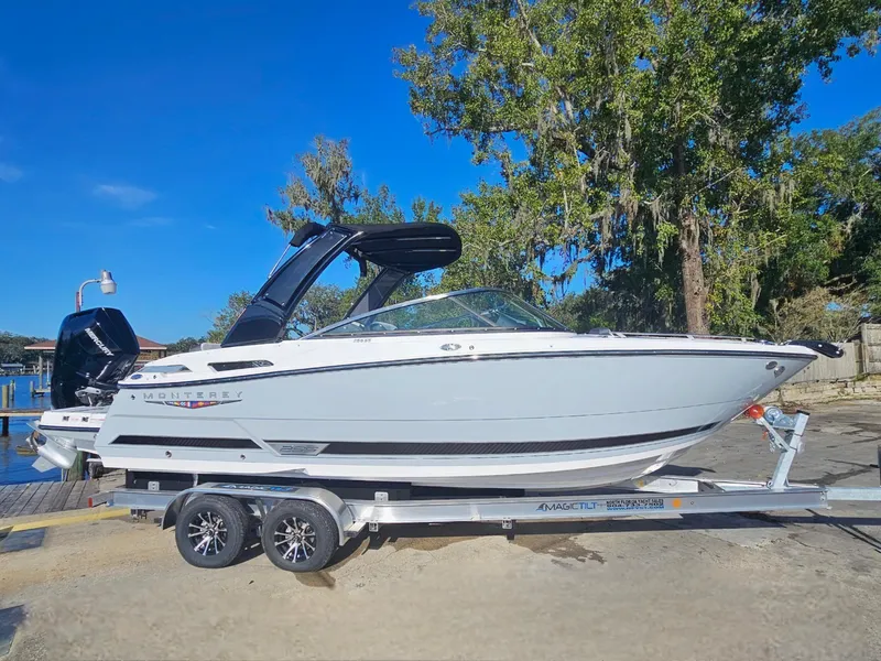 Slide: The Image of 2025 Monterey 255SS boat on trailer, parked outdoors under clear blue sky. - 4