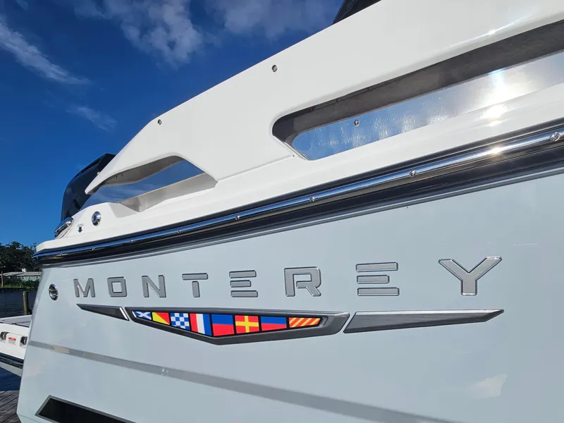 Slide: The Image of 2025 Monterey 255SS boat, close-up of logo and nautical flags under clear blue sky. - 9