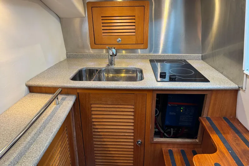 Slide: The Image of 2006 Glacier Bay 3470 Ocean Runner galley with sink, stove, and wooden cabinetry. - 13