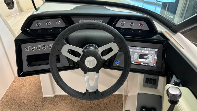 Slide: The Image of 2025 MasterCraft NXT23 boat dashboard with steering wheel and control panel. - 23