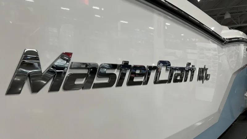 Slide: The Image of 2025 MasterCraft NXT23 boat logo on sleek white hull. - 31