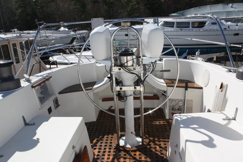 Slide: The Image of 1976 C&C 38 sailboat cockpit with steering wheel and wooden deck, docked in marina. - 19