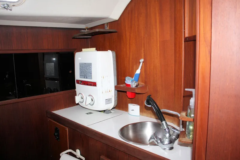 Slide: The Image of 1976 C&C 38 yacht interior with sink and water heater in wooden cabinetry. - 26