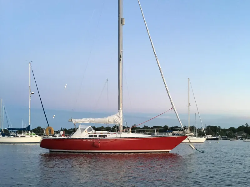 Slide: The Image of Red 1976 C&C 38 sailboat anchored on calm water under a clear sky. - 4