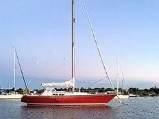 Slide: The Image of Red 1976 C&C 38 sailboat anchored on calm water at sunset. - 5
