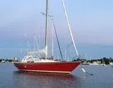 Slide: The Image of Red 1976 C&C 38 sailboat anchored on calm water under a clear sky. - 6