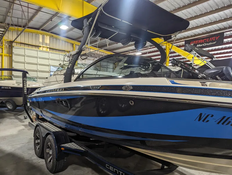 Slide: The Image of 2014 Centurion Enzo SV233 boat in a warehouse, featuring a sleek blue and black design. - 2