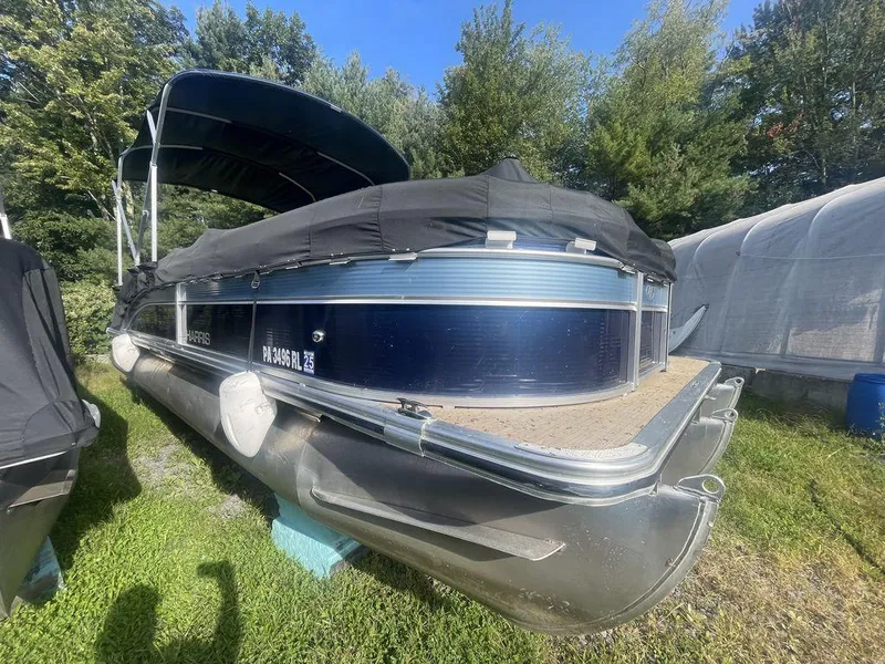 Slide: The Image of 2021 Harris CRUISER 250 CW P3 pontoon boat with cover, parked on grass. - 1