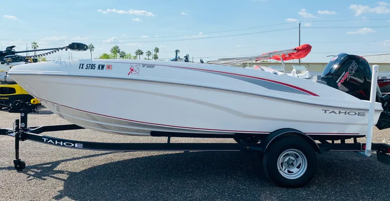 Slide: The Image of 2024 Tahoe T18 boat on trailer, white with red accents, parked outdoors. - 2