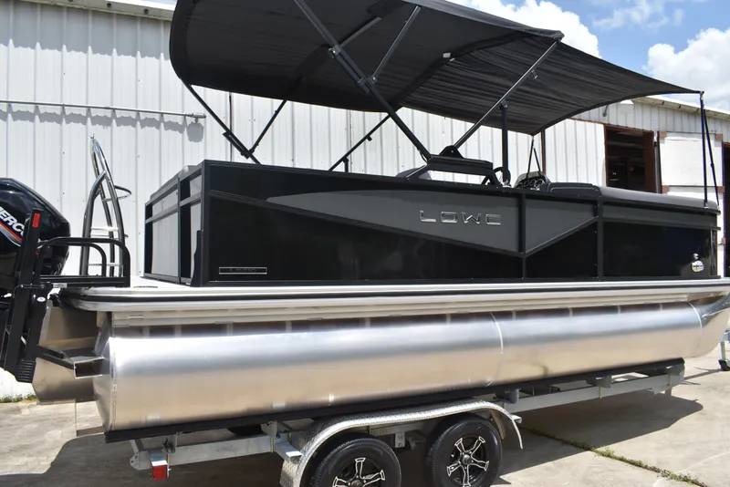 Slide: The Image of 2025 Lowe LS210WT TL pontoon boat with canopy on trailer, parked outdoors. - 3