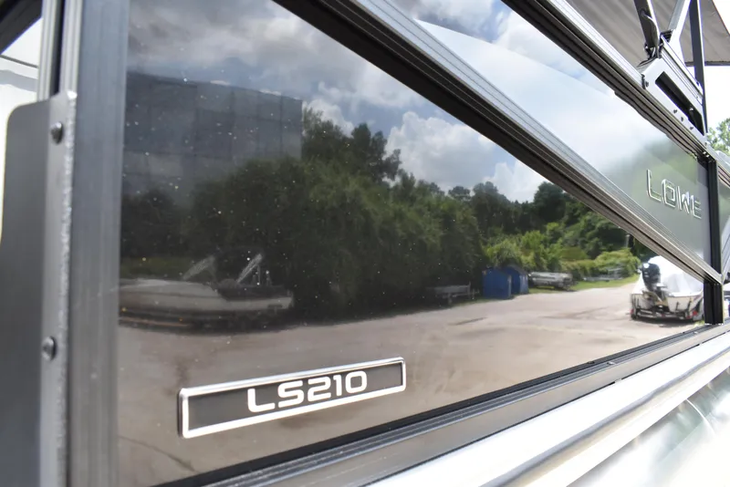 Slide: The Image of 2025 Lowe LS210WT TL boat with reflective black paneling in outdoor setting. - 4