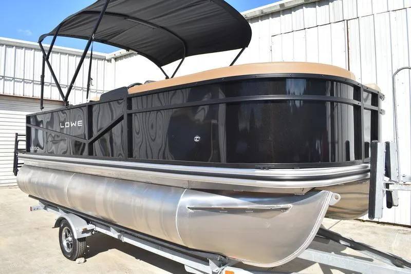 Slide: The Image of 2025 Lowe LS190 pontoon boat with black exterior and canopy on a trailer. - 2