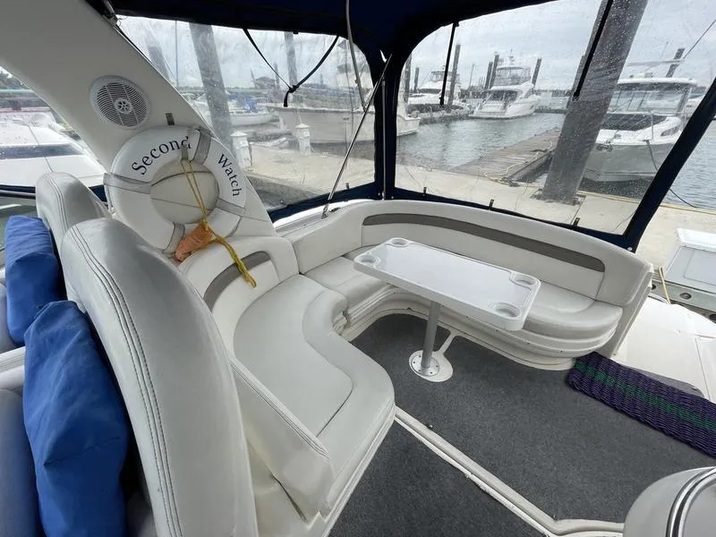 Slide: The Image of 2003 Sea Ray 340 Sundancer interior with white seating and marina view. - 14