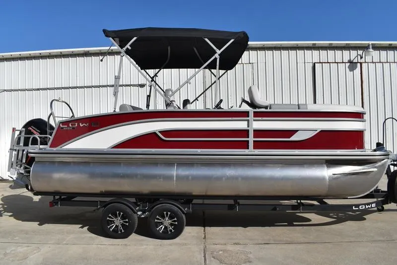 The Image of 2023 Lowe SS 210DL TL pontoon boat with red and white design, parked on a trailer. - 0