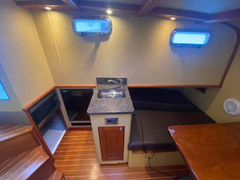 Slide: The Image of Interior of 2011 Sabre Custom Yachtfish with kitchenette, wooden flooring, and seating area. - 19