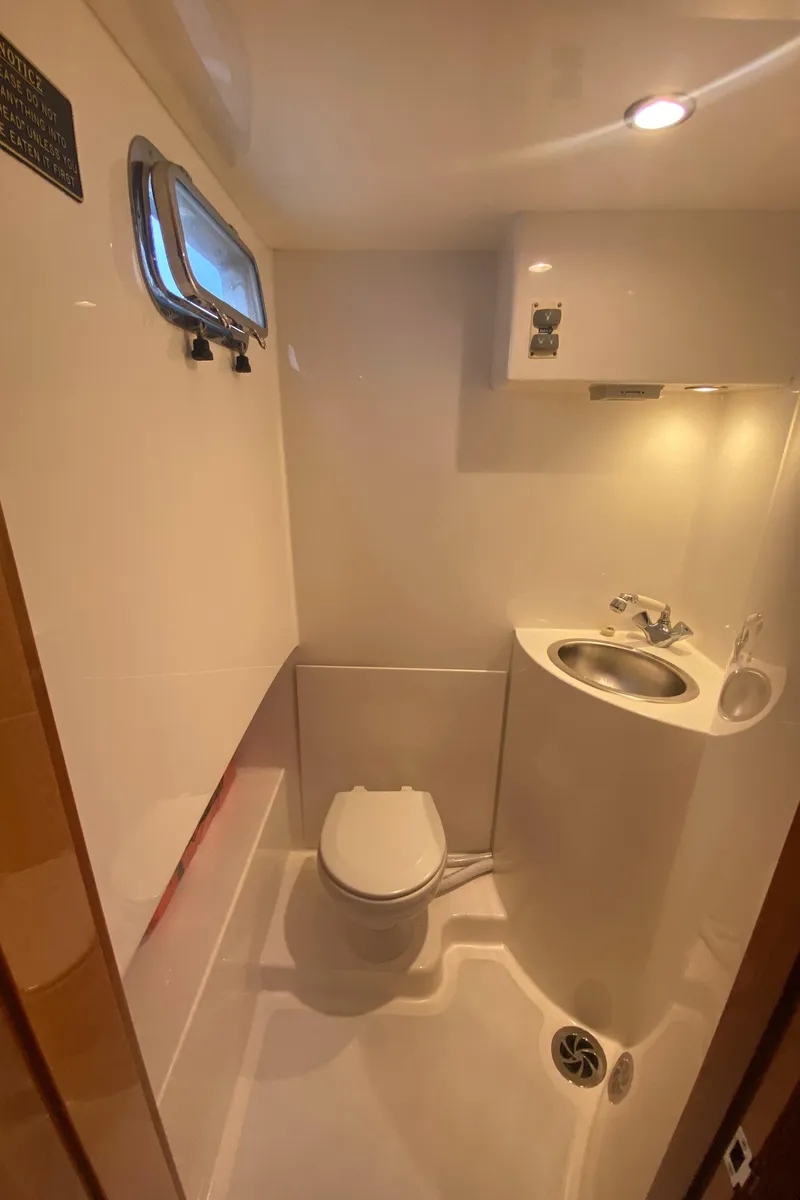 Slide: The Image of 2011 Sabre Custom Yachtfish bathroom with compact toilet, sink, and porthole window. - 21