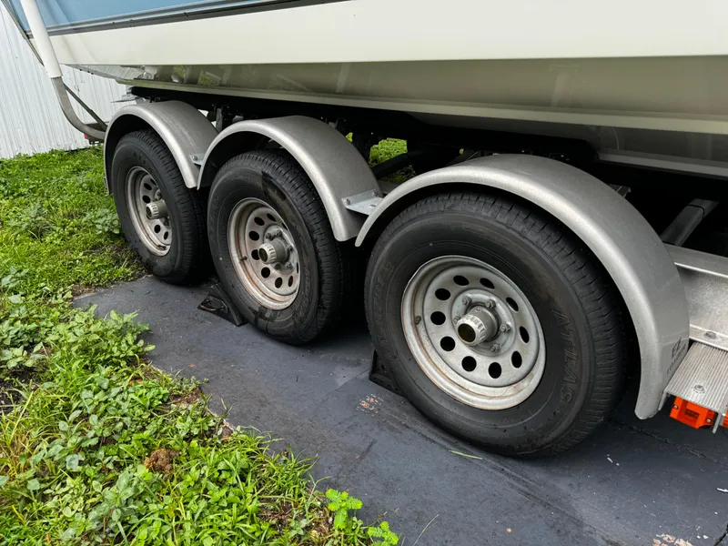 Slide: The Image of 2020 Mako 284 CC boat trailer with triple axles on grass. - 39