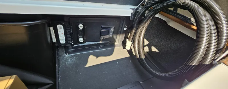 Slide: The Image of 2025 Malibu 25LSV interior storage compartment with control panel and coiled hose. - 15