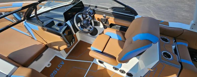 Slide: The Image of Interior of 2025 Malibu 25LSV boat with brown and blue seating, modern dashboard. - 19