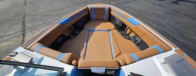 Slide: The Image of 2025 Malibu 25LSV boat interior with tan and blue seating, cup holders, and sleek design. - 25
