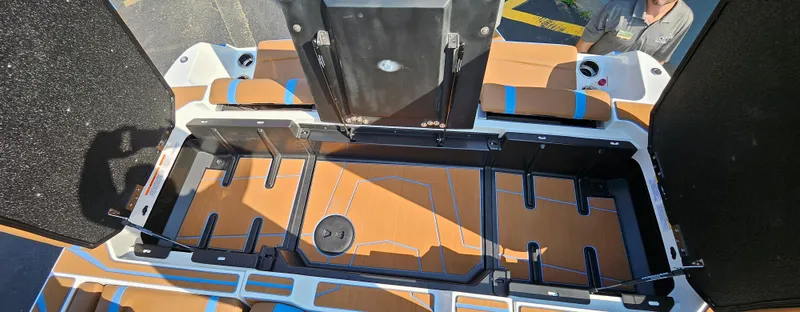 Slide: The Image of 2025 Malibu 25LSV boat interior storage compartment with open hatches and cushioned seating. - 9