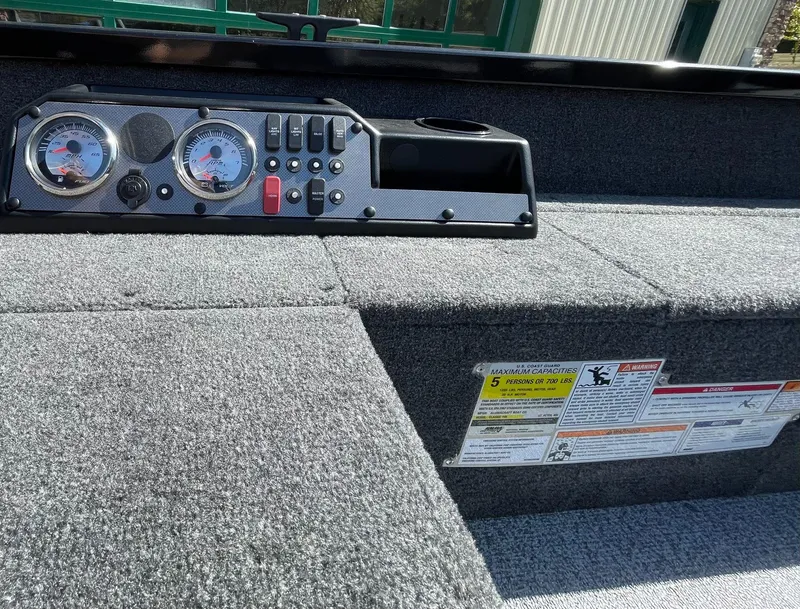 Slide: The Image of 2024 Alumacraft Classic 165 Tiller dashboard with gauges and capacity warning labels. - 6