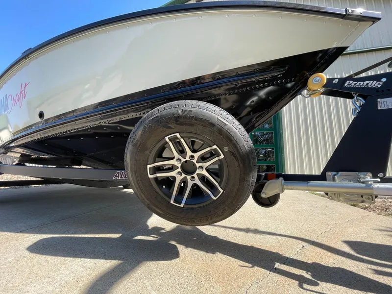 Slide: The Image of 2024 Alumacraft Classic 165 Tiller boat on trailer, close-up of wheel and hull. - 8