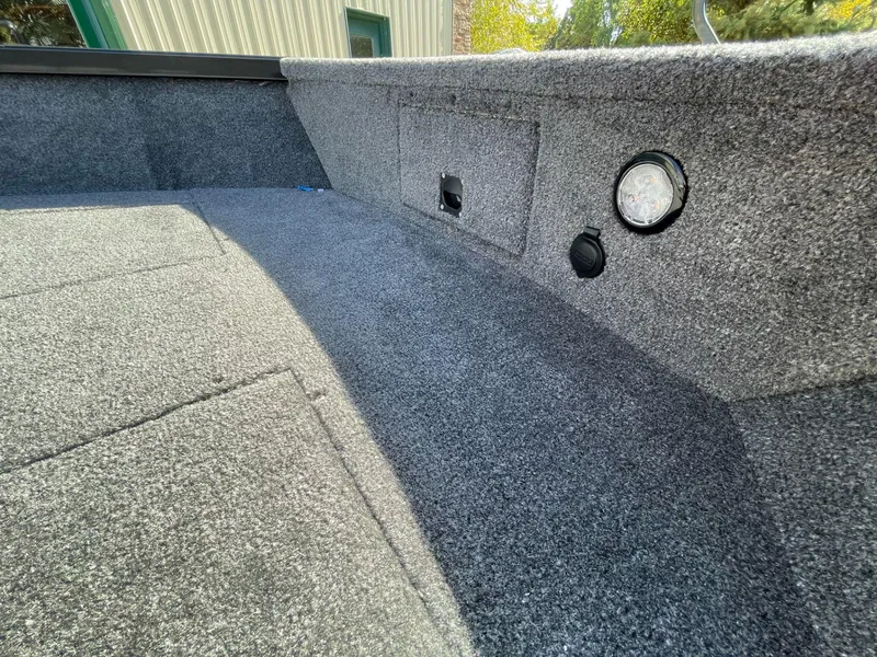 Slide: The Image of 2024 Alumacraft Classic 165 Tiller interior with carpeted flooring and storage compartments. - 9