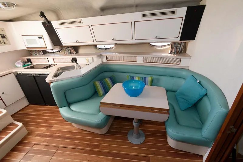 Slide: The Image of 1992 Regal Commodore 402 yacht interior with teal seating, wooden flooring, and modern kitchen amenities. - 11