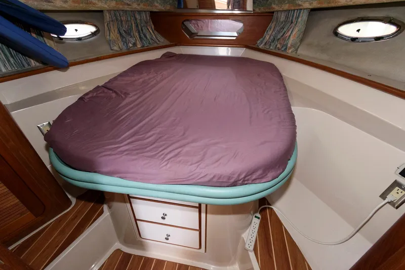 Slide: The Image of 1992 Regal Commodore 402 cabin with bed, wood accents, and portholes. - 15