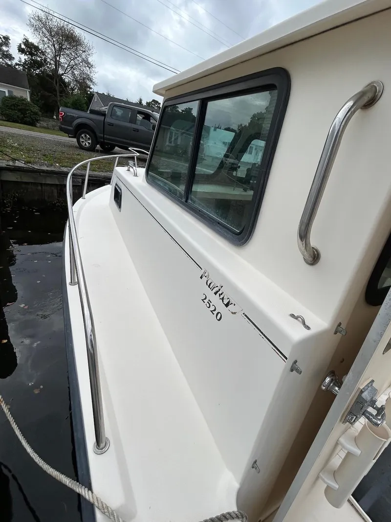 Slide: The Image of 2001 Parker 2520 Modified Vee Sport Cabin boat docked, side view with railing and window. - 4