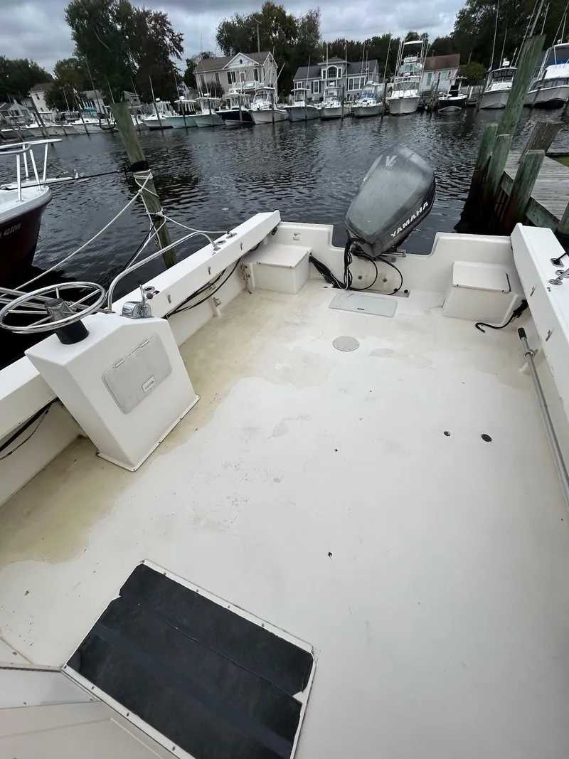 Slide: The Image of 2001 Parker 2520 Modified Vee Sport Cabin boat docked, spacious deck, outboard motor visible. - 6
