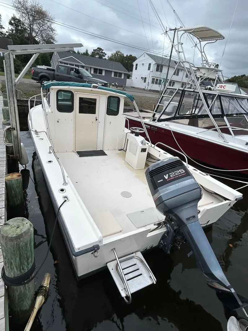 Slide: The Image of 2001 Parker 2520 Modified Vee Sport Cabin boat docked, featuring a V225 outboard motor. - 7