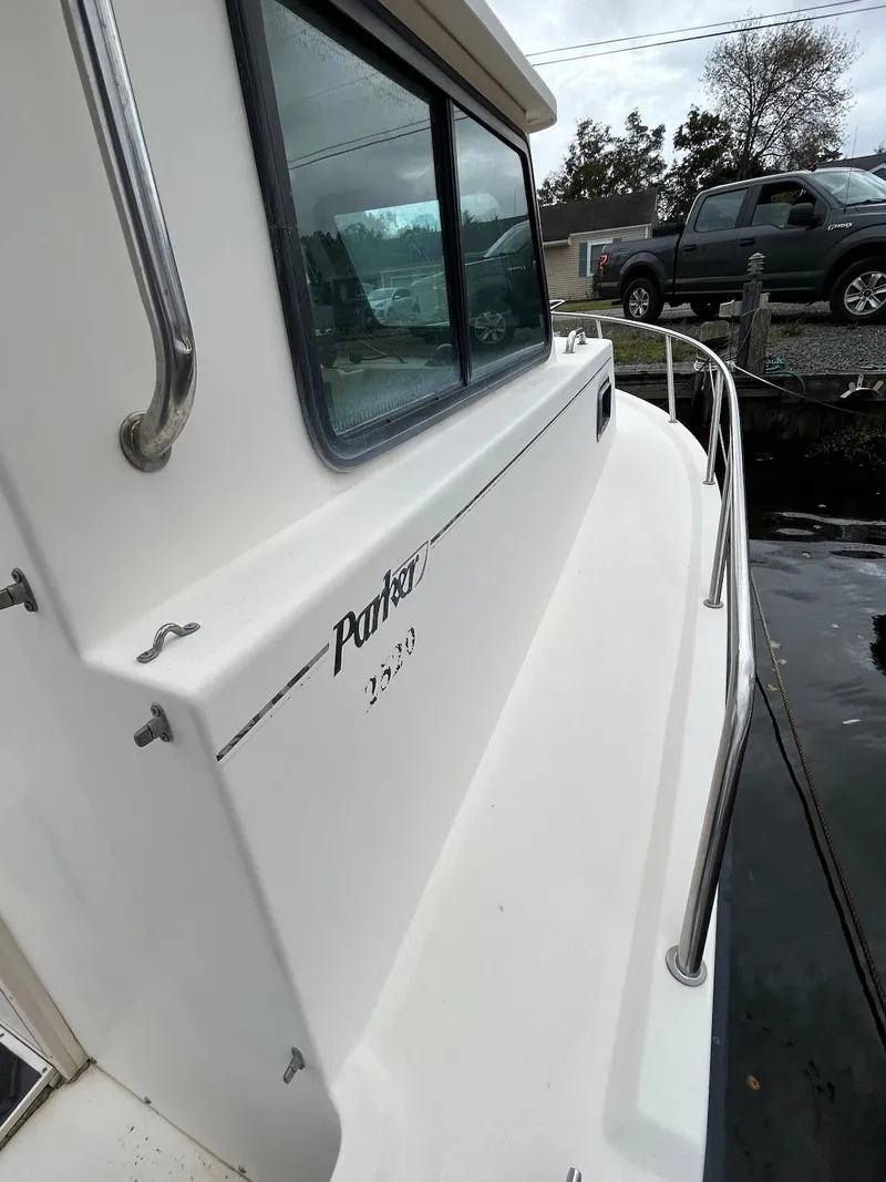 Slide: The Image of 2001 Parker 2520 Modified Vee Sport Cabin boat docked, side view with railing and window. - 9