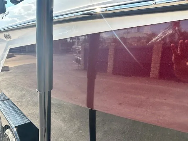 Slide: The Image of 2022 Nautique G23 boat with glossy maroon finish reflecting sunlight. - 25