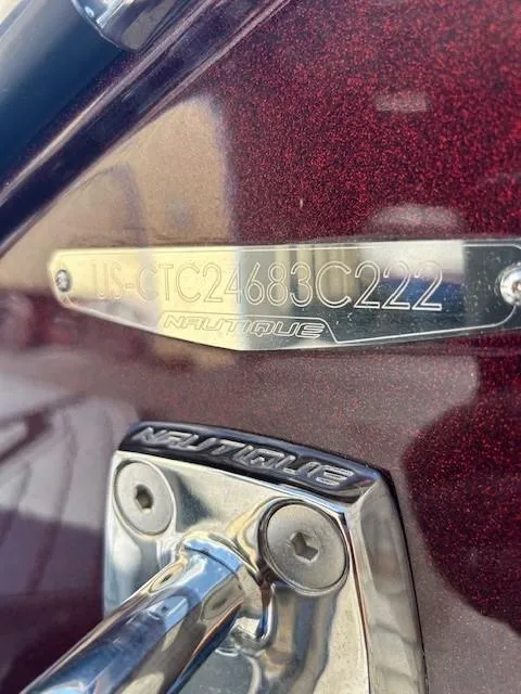 Slide: The Image of 2022 Nautique G23 boat identification plate with serial number on maroon surface. - 26